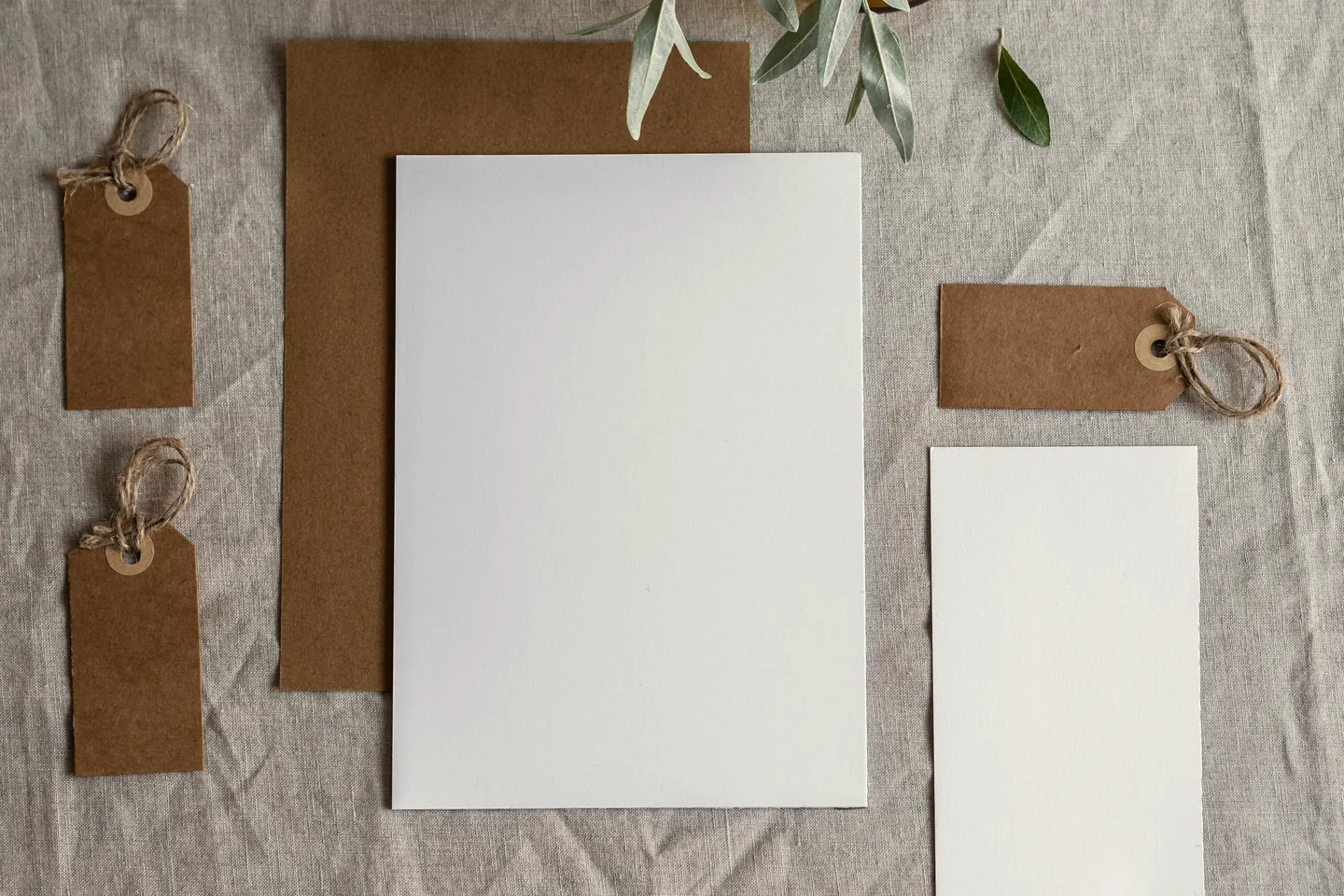 Letterhead, envelope stock and kraft tags laid out on natural linen