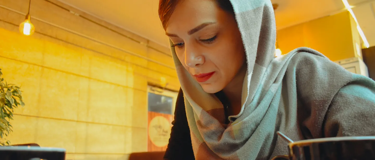 A woman reading on her phone at a cafe table in warm afternoon light