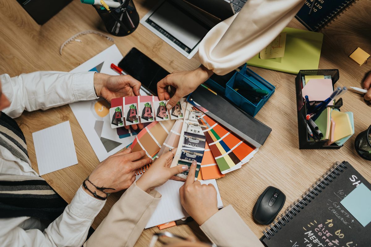 A team planning a brand relaunch, comparing color swatches and printed samples on a wooden worktable
