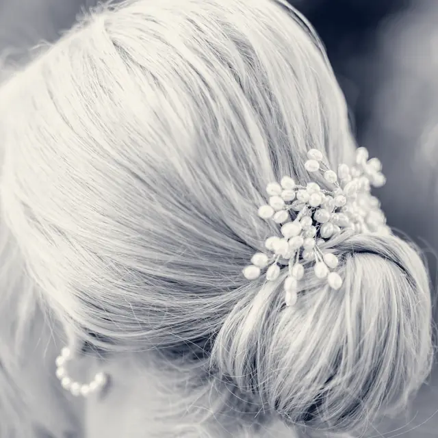 A smooth chignon finished with delicate floral pins