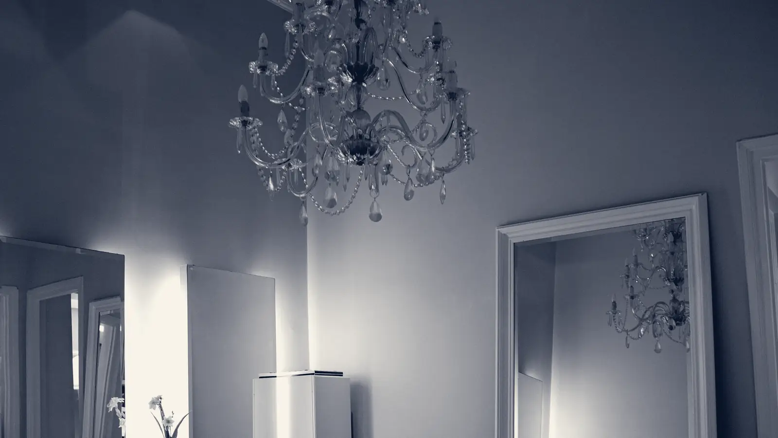 A refined salon with a crystal chandelier and a tall mirror
