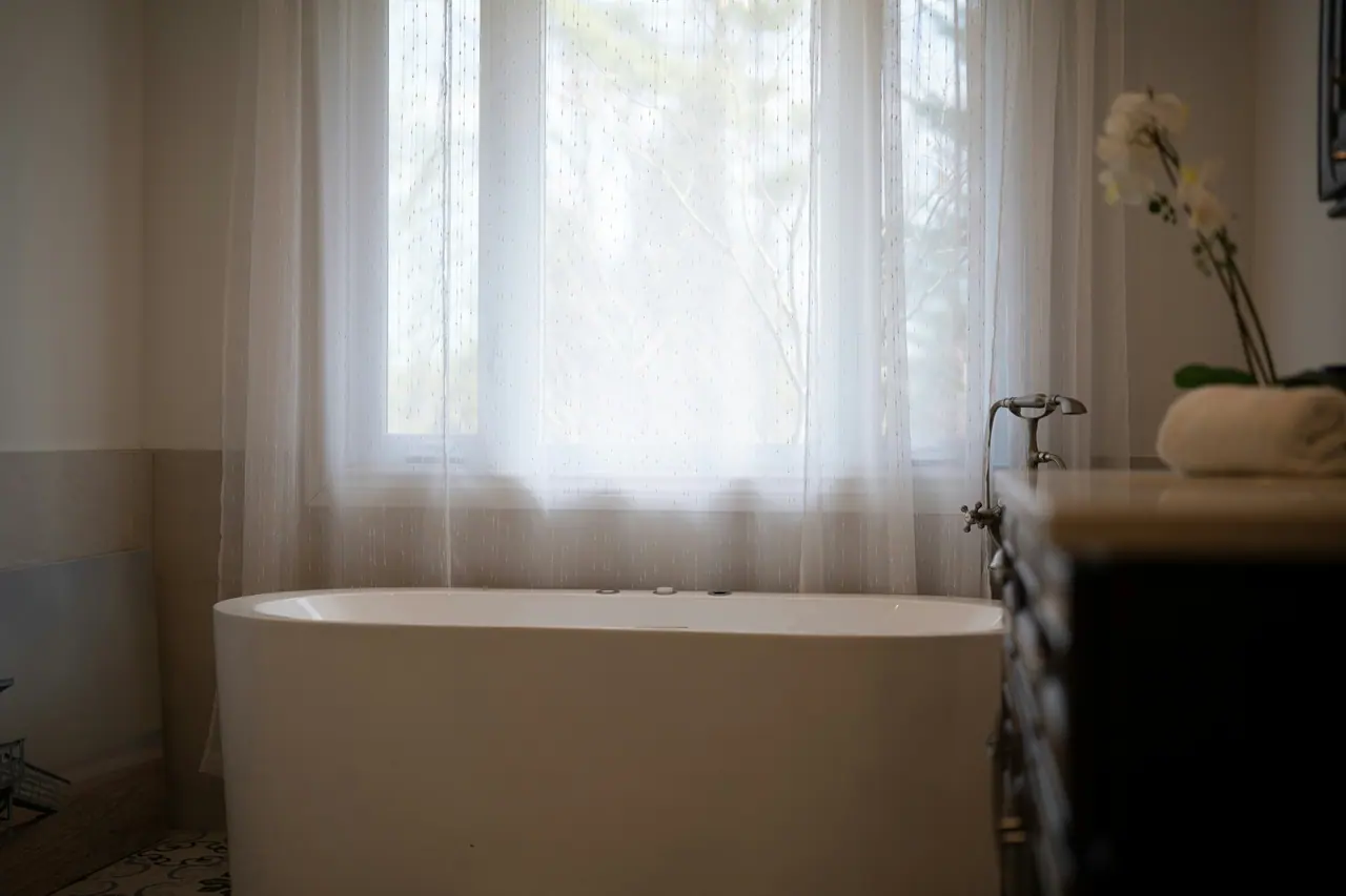 Bright suite with a freestanding tub and sheer curtains