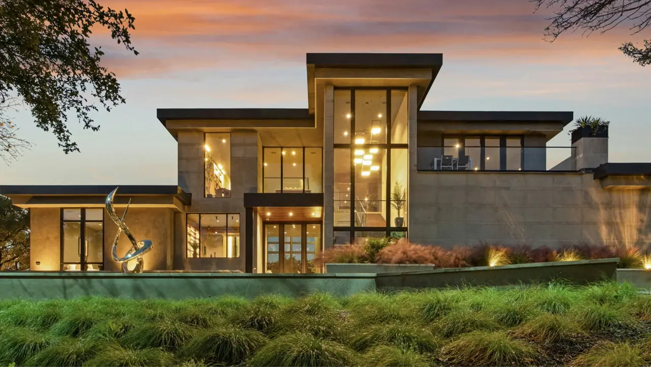 Contemporary stone and glass residence glowing at dusk