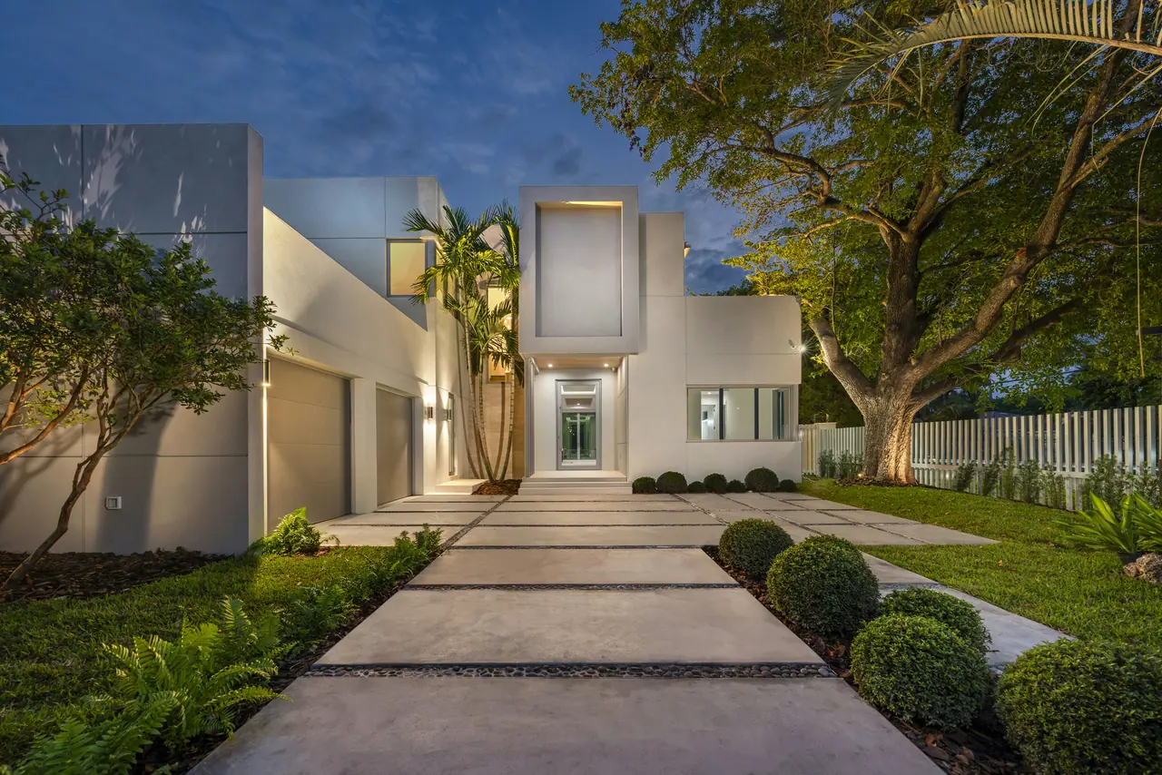 Illuminated pathway to a white modern home