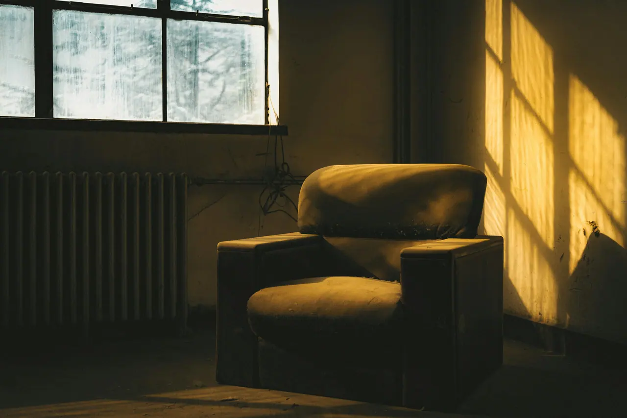 A worn armchair bathed in golden window light